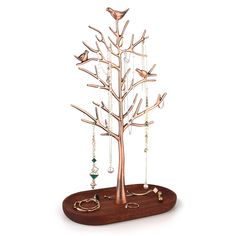 a metal tree with birds on it and jewelry hanging from the branches, in front of a white background