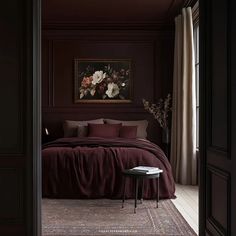 a bedroom with dark colored walls and bedding, along with a painting on the wall