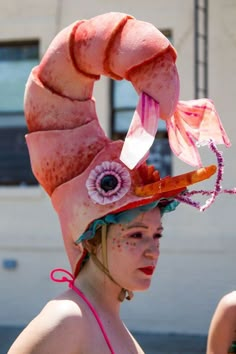 a woman wearing a pink hat with an orange flower on it's head and eyes