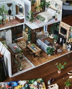 a doll house is shown with furniture and accessories on the floor, as well as potted plants