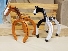 two wooden horse sculptures sitting on top of a bed next to each other in front of a bench