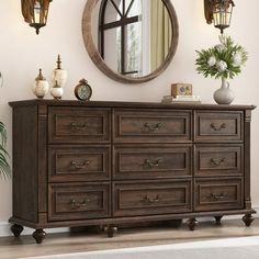 a wooden dresser sitting under a round mirror