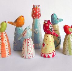 several colorful ceramic figurines are lined up on a white surface, each with different designs and colors