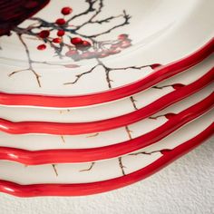 four red and white plates stacked on top of each other with branches painted on them