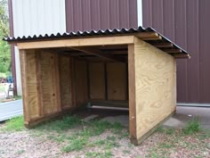 a dog house made out of plywood is shown in front of a metal building