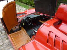 the interior of an old red sports car with its door open and leather seats folded down