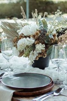 the table is set with plates, silverware and floral centerpieces on it