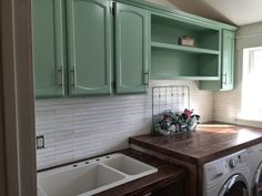 a washer and dryer in a small room with green cabinets on the wall