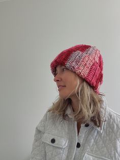 a woman wearing a red and white knitted hat while standing in front of a wall