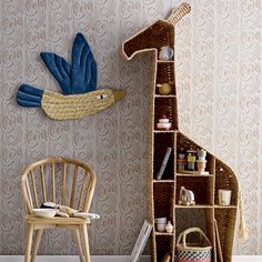 a giraffe shaped book shelf next to a chair and wallpapered wall