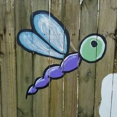 a painting on the side of a wooden fence with a dragonfly painted on it