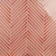 a close up view of a herringbone tile pattern in red and pink tones,