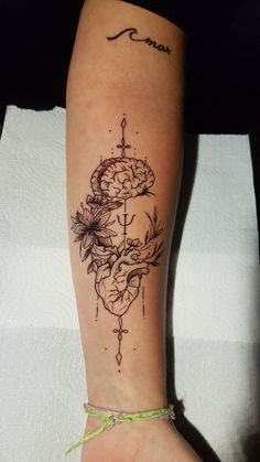 a woman's foot with a tattoo on it and flowers in the middle of her leg