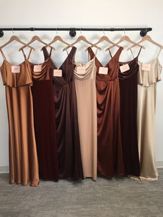 six dresses hanging on a rack in front of a wall