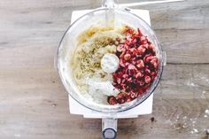 ingredients in a food processor to make cranberry muffins on a wooden table