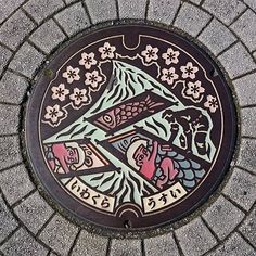 a manhole cover with an image of two fish and flowers painted on the side