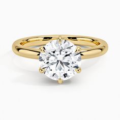 a yellow gold engagement ring with a round cut diamond in the center, on a white background