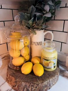 some lemons are sitting on a tree stump next to a jar of lemonade