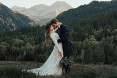 a bride and groom kissing in the mountains