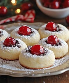 cookies with cherries and powdered sugar on a plate