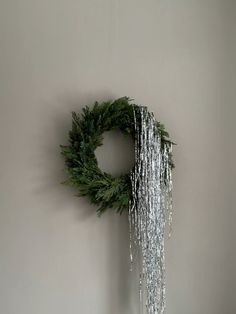 a green wreath hanging on the wall with chains attached to it's sides,