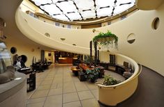 the inside of a large building with lots of windows and plants on it's walls