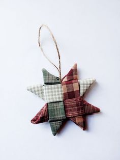 a plaid star ornament hanging from a string on a white background with twine