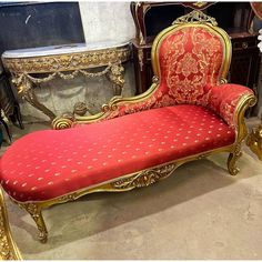 a red and gold chaise lounge in a room with other antique furniture on display