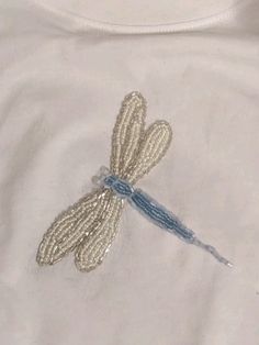 a white shirt with a dragonfly embroidered on it