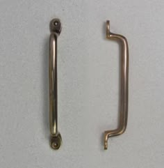 two metal handles on a white surface one has a screw and the other is a handle