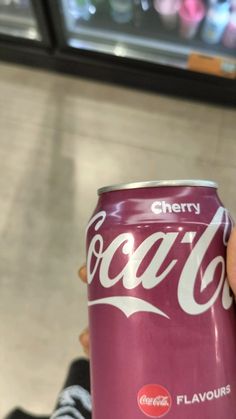 a person holding a can of coca - cola in their hand