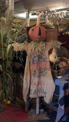 an old scarecrow with hay and pumpkins on display