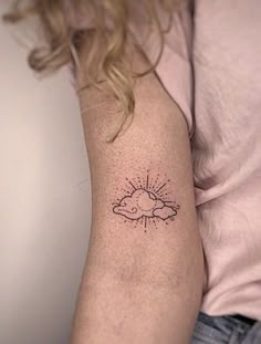 a woman's arm with a small sun and cloud tattoo on her left arm