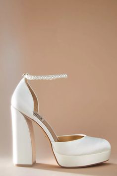 a pair of white high heeled shoes with a beaded ankleband on top