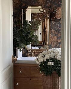 there is a basket with flowers on the counter in this bathroom sink and mirror above it