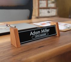 a desk with a sign that says adam miller coffee manager on it and a laptop in the background