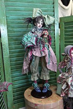 two creepy dolls sitting next to each other in front of green shutters