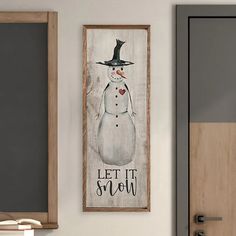 a snowman with a black hat is hanging on the wall next to a door