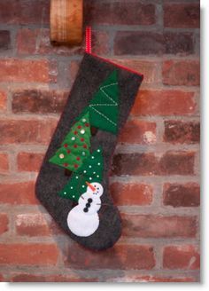 a christmas stocking hanging on a brick wall with a snowman and tree decoration