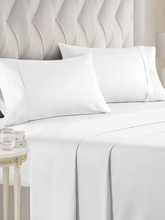 a bed with white sheets and pillows on it