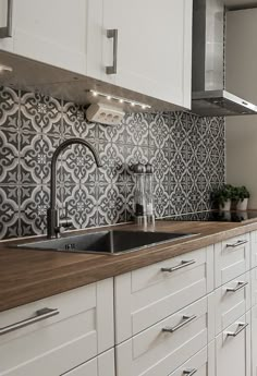 a kitchen with white cabinets and black and white tiles on the backsplashes