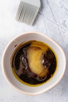 a white bowl filled with liquid next to a brush on top of a countertop