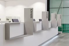 an office lobby with white walls and gray chairs on the desks that have service signs attached to them