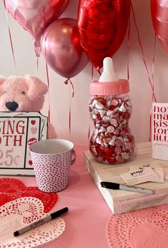 valentine's day table setting with pink and red balloons, heart shaped candies, coffee cup, teddy bear