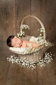 a baby is sleeping in a basket with flowers