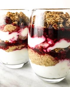 two glasses filled with dessert sitting on top of a table