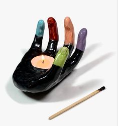 a candle holder made to look like a hand with five fingers holding a lit candle