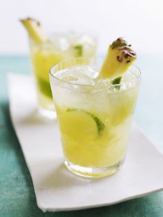 two glasses filled with lemonade and lime on top of a white plate next to each other