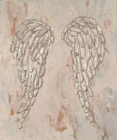 two angel wings painted on a white and beige background with brown paint streaks in the foreground