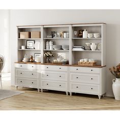 a large white bookcase with drawers and baskets on the top, in front of a dining room table